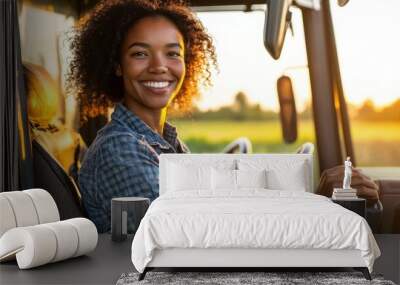 A young woman smiles from the driver\'s seat of a truck during sunset in a rural landscape Wall mural